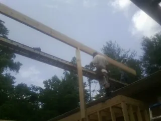 Carpenter setting a ridge beam over a new addition frame — Ice Dam Removal by Roofing Brothers in Jacksboro