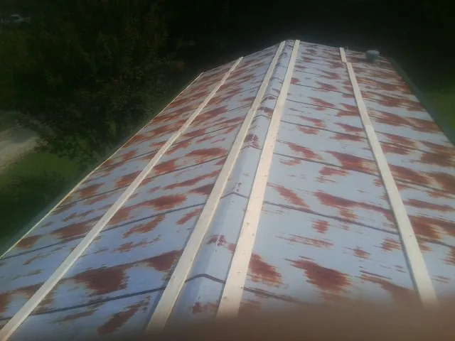 Rusted metal roof panels with new wood purlins before replacement in Jacksboro