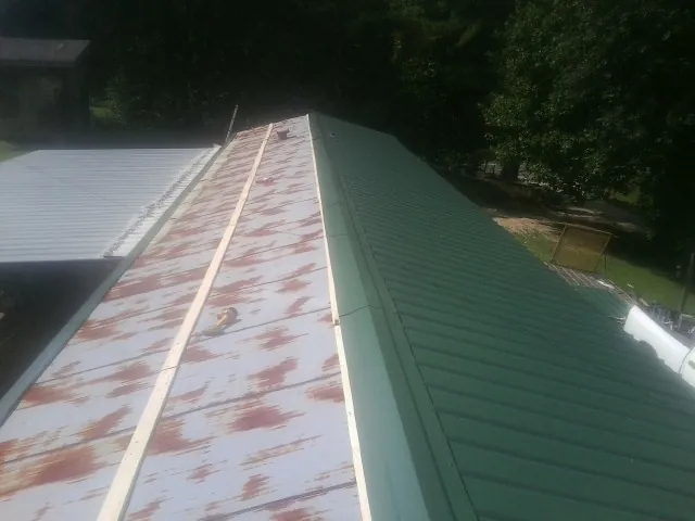 Old rusted panels beside newly installed green metal roofing — Wind Damage Roof Repair by Roofing Brothers in Jacksboro