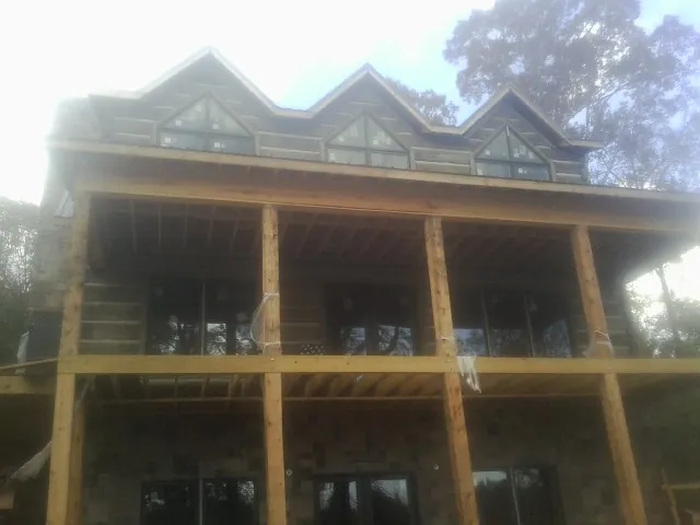 Dormers and porch framing on a large log home under construction — Roof Coating work by our crew in Jacksboro