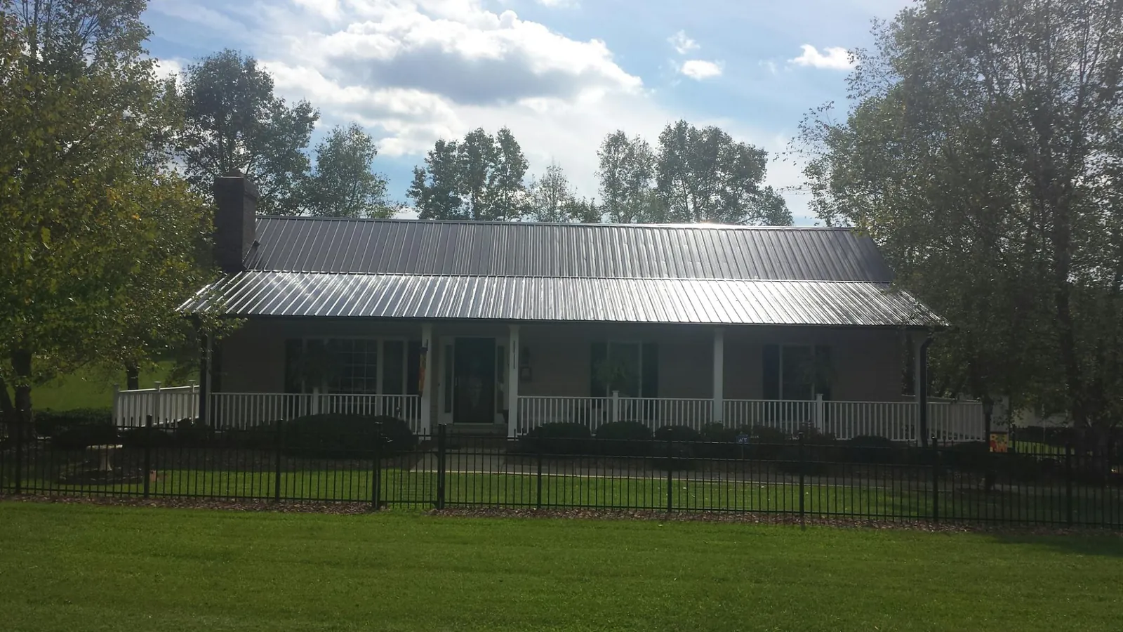 Gray metal roof on a brick ranch with a full width front porch — Gutter Guard Installation work by our crew in Jacksboro