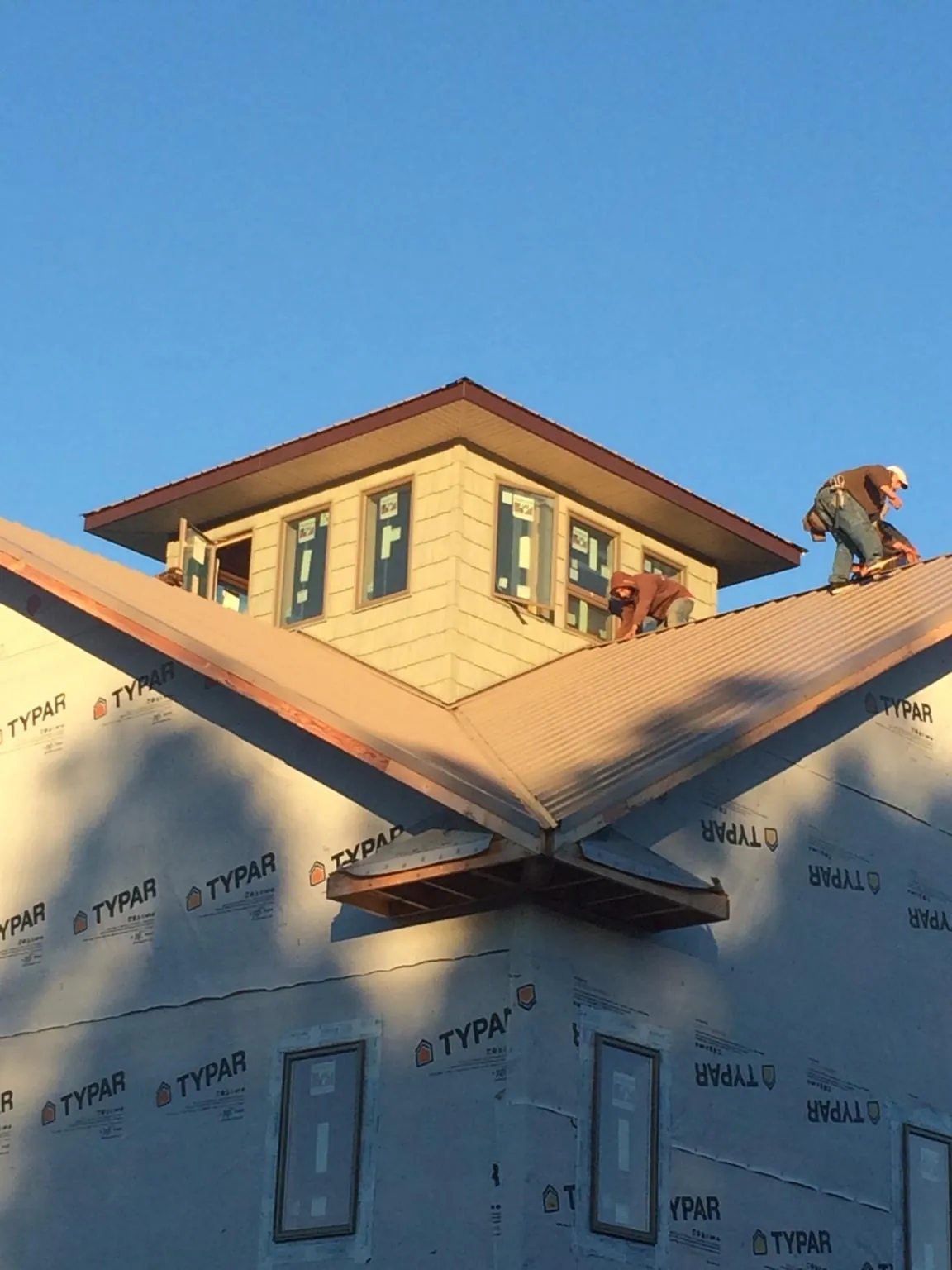 Roofers working around a rooftop cupola on a new metal roof at sunset — Roof Waterproofing in Jacksboro by Roofing Brothers
